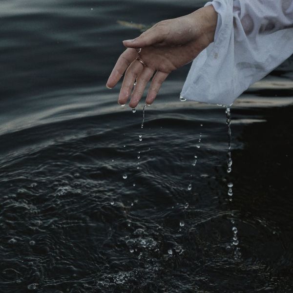 Woman performing a gentle, fluid movement in a bright, calm space.
